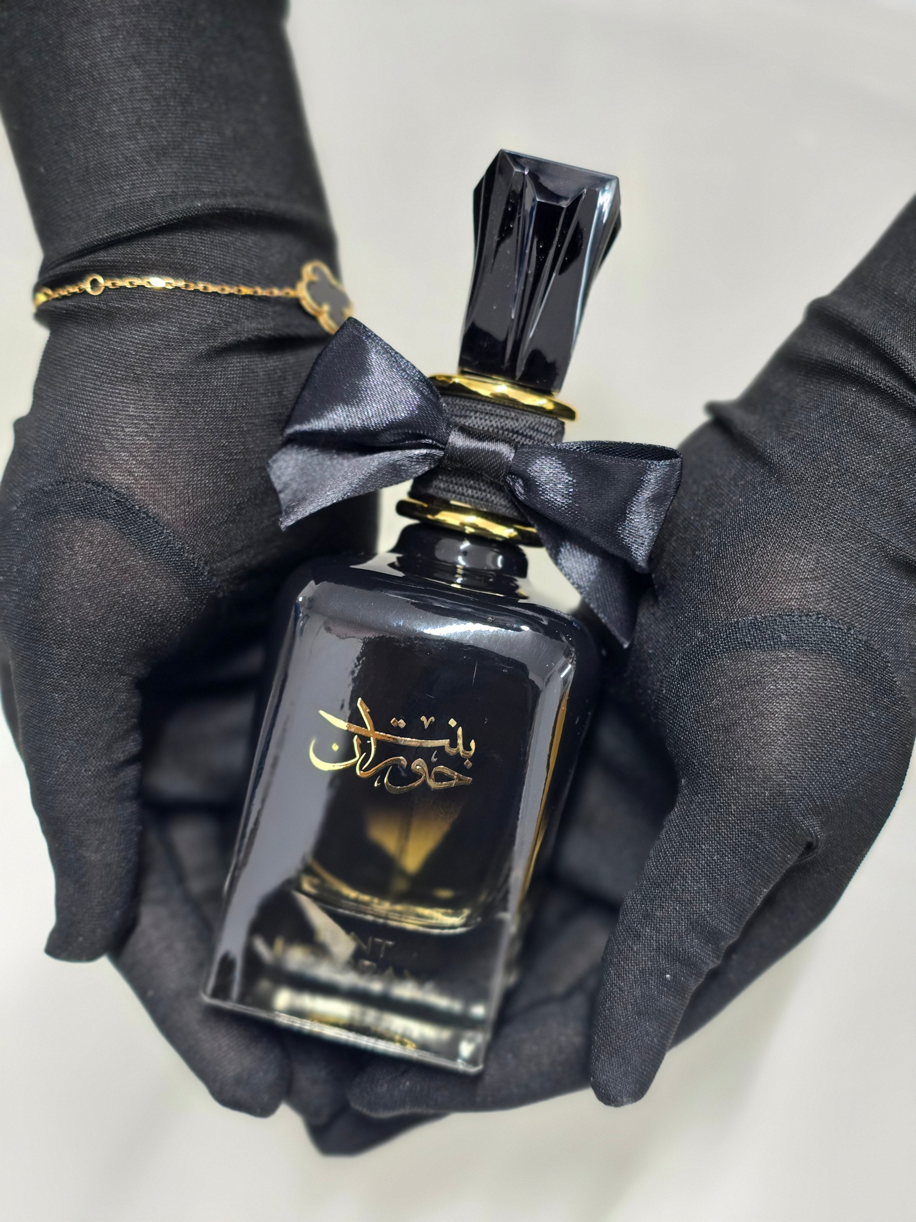 Black perfume bottle with gold accents on a light background